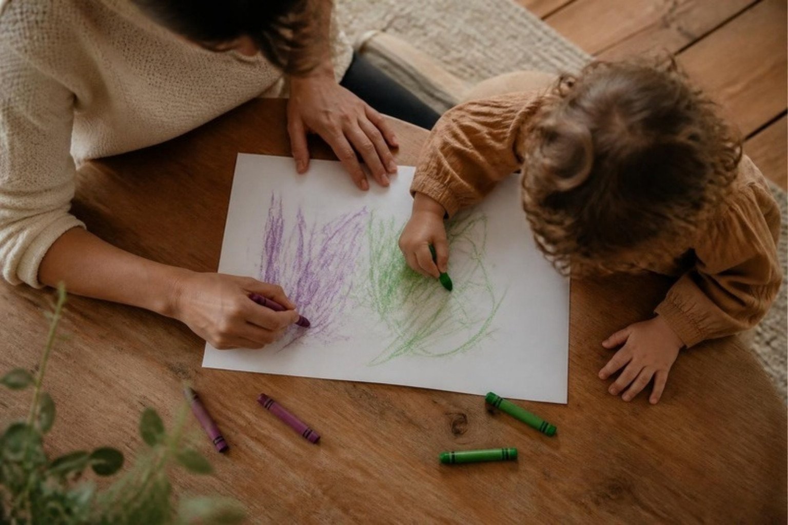 Un adulto y un niño dibujan juntos en una mesa de madera